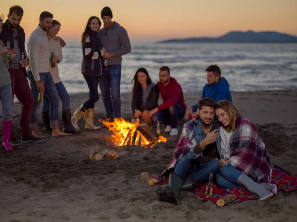 Paar Met Behulp Van Mobiele Telefoon Tijdens Strandfeest Met Vrienden — Stockfoto