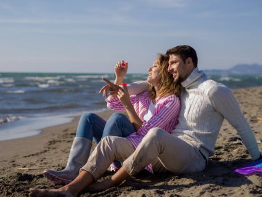 Genç çift sonbahar günü sahilde eğleniyor ve sabun köpükleri yapıyor.