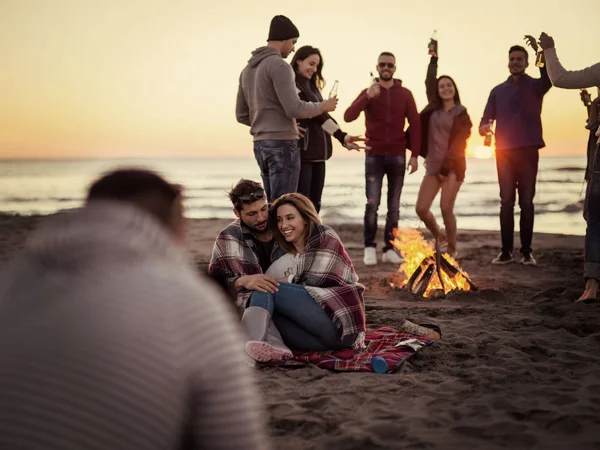 Pareja Joven Sentada Con Amigos Alrededor Campfire Beach Atardecer Bebiendo —  Fotos de Stock