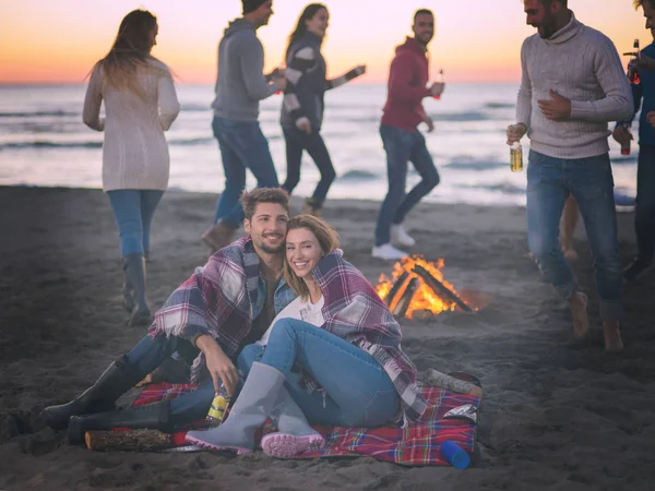 Pareja Joven Sentada Con Amigos Alrededor Campfire Beach Atardecer Bebiendo —  Fotos de Stock