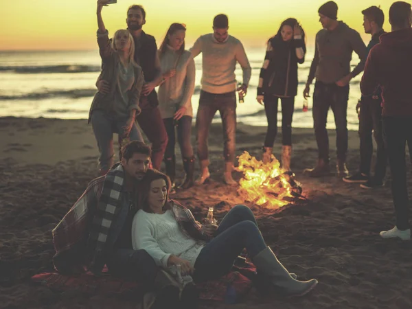 Pareja Joven Sentada Con Amigos Alrededor Campfire Beach Atardecer Bebiendo — Foto de Stock