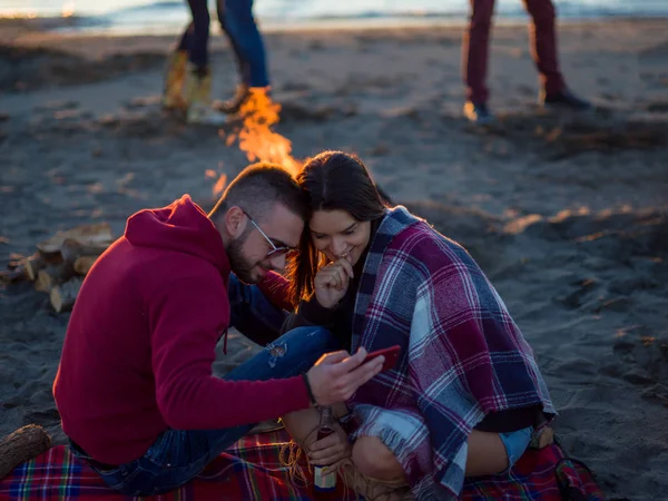 Paar Met Behulp Van Mobiele Telefoon Tijdens Strandfeest Met Vrienden — Stockfoto