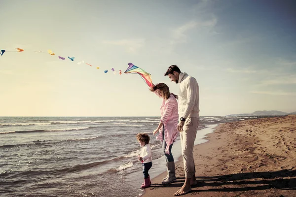 秋天里有孩子休息和在海滩放风筝玩乐的年轻家庭 — 图库照片
