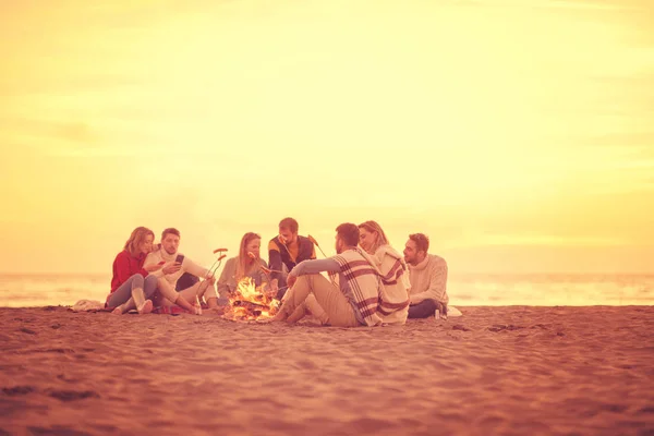 Group Young Friends Sitting Fire Autumn Beach Grilling Sausages Drinking — Stock Photo, Image