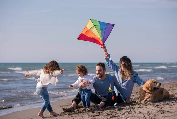 秋天里 一个快乐的年轻家庭带着孩子们在海滩上与狗和风筝玩耍 — 图库照片