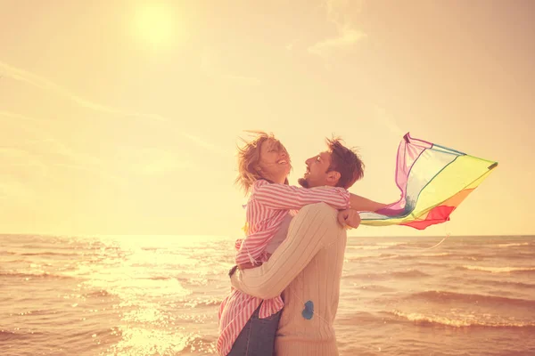秋の日のフィルターでビーチで凧と遊んで楽しむ若いカップル — ストック写真