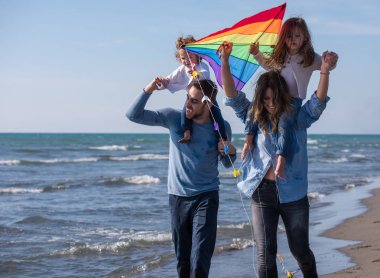 Genç bir aile, çocukları dinleniyor ve sonbahar günü kumsalda uçurtmayla eğleniyorlar.