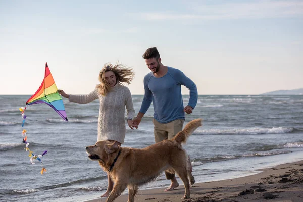 若いカップルが楽しんで犬 秋の日にビーチにカイトで遊んで — ストック写真