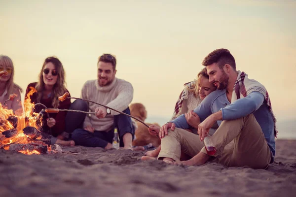 Группа Молодых Друзей Сидящих Костра Осеннем Пляже Жарящих Сосиски Пьющих — стоковое фото