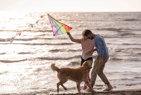 若いカップルが楽しんで犬 秋の日にビーチにカイトで遊んで — ストック写真