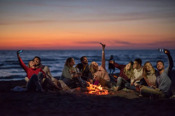 Gruppo Amici Che Usano Cellulari Intorno Falò Durante Festa Spiaggia — Foto Stock