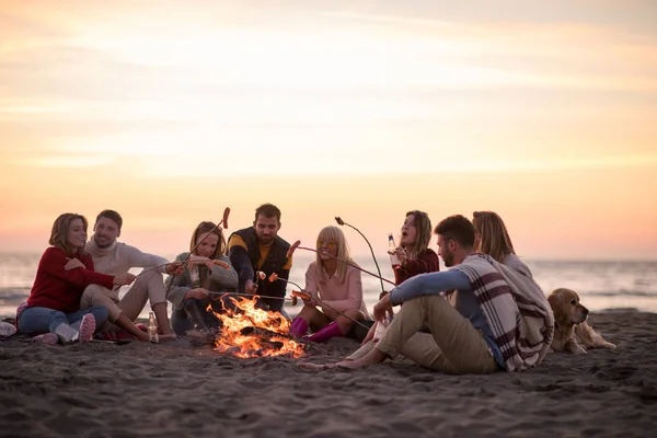 Grupo Jóvenes Amigos Sentados Junto Fuego Playa Otoño Asando Salchichas — Foto de Stock