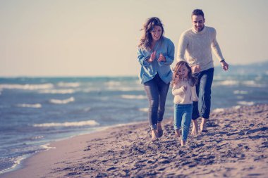 Çocukların dinlendiği ve sonbahar günü kumsalda eğlendiği bir aile.