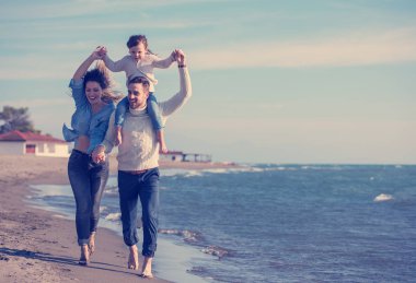 Çocukların dinlendiği ve sonbahar günü kumsalda eğlendiği bir aile.