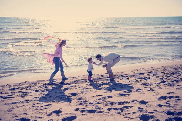 秋の日にはビーチでカイトと一緒に休んで楽しむ子供たちを持つ若い家族 — ストック写真