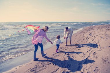 Genç bir aile, çocukları dinleniyor ve sonbahar günü kumsalda uçurtmayla eğleniyorlar.