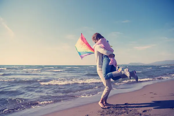 在秋天的沙滩上玩风筝的年轻夫妇 — 图库照片