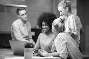 Modern gece ofis içi beyin fırtınası ve dizüstü bilgisayar üzerine çalışan çok ırklı bir girişim ekibi.