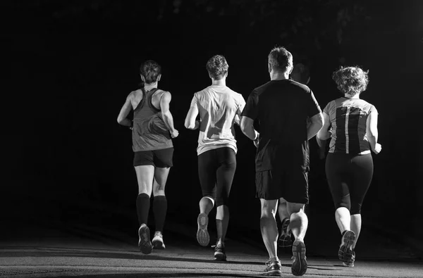 group of healthy people jogging in city park, runners team at night training