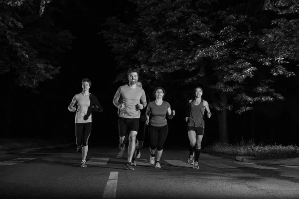 都会の公園でジョギングをしている健康な人たちや夜のトレーニングで — ストック写真