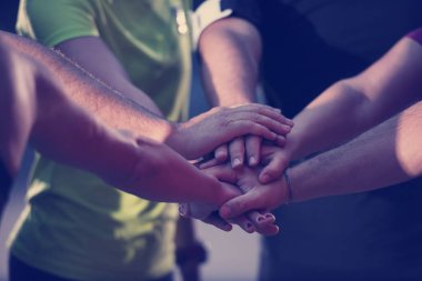 Bir grup sağlıklı koşucu antrenmandan sonra başarıyı kutlarken birbirlerine beşlik çakıyor..
