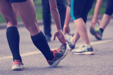 Sağlıklı koşucular ısınıyor ve sabah antrenmanından önce şehir parkında esniyorlar.