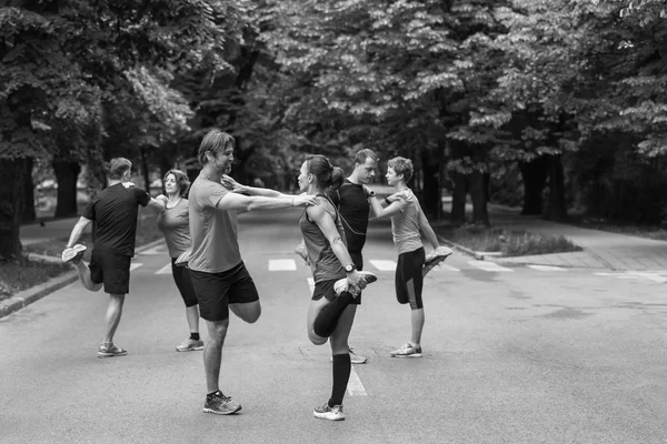 健康なランナーチームが朝のトレーニングの前に街の公園で温暖化とストレッチ — ストック写真