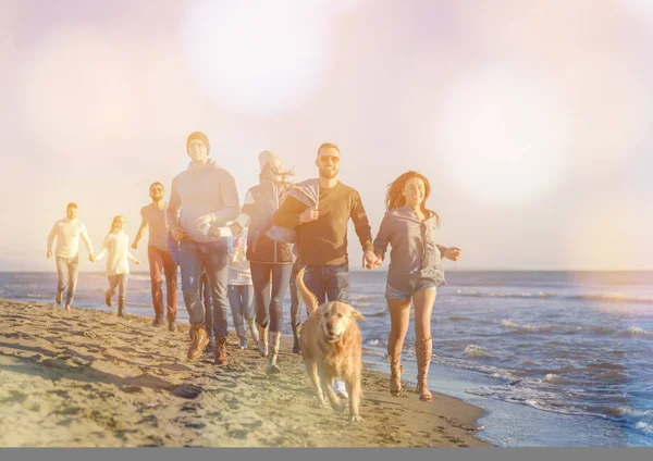 一群年轻的朋友在秋天的一天里一起在海滩上跑步 — 图库照片