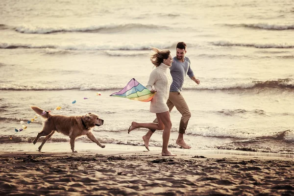 Pareja Joven Divirtiéndose Jugando Con Perro Cometa Playa Día Otoño —  Fotos de Stock