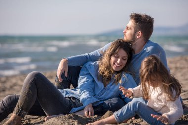 Çocukların dinlendiği ve sonbahar günü kumsalda eğlendiği bir aile.