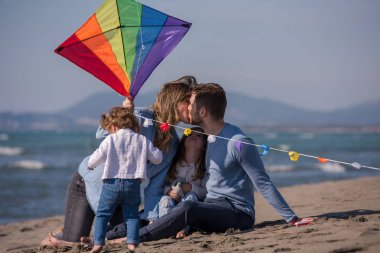 Genç bir aile, çocukları dinleniyor ve sonbahar günü kumsalda uçurtmayla eğleniyorlar.
