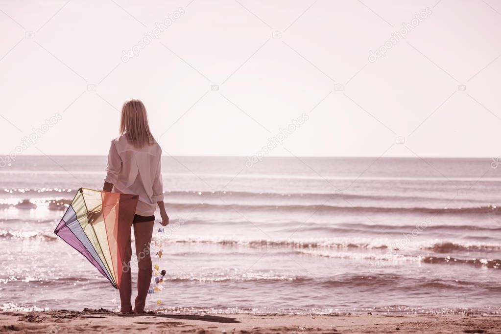 Beautiful Young Woman having fun with a kite at Beach on autumn day filter