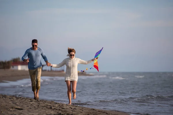 秋の日にはビーチで凧揚げを楽しみながら遊ぶ若いカップル — ストック写真