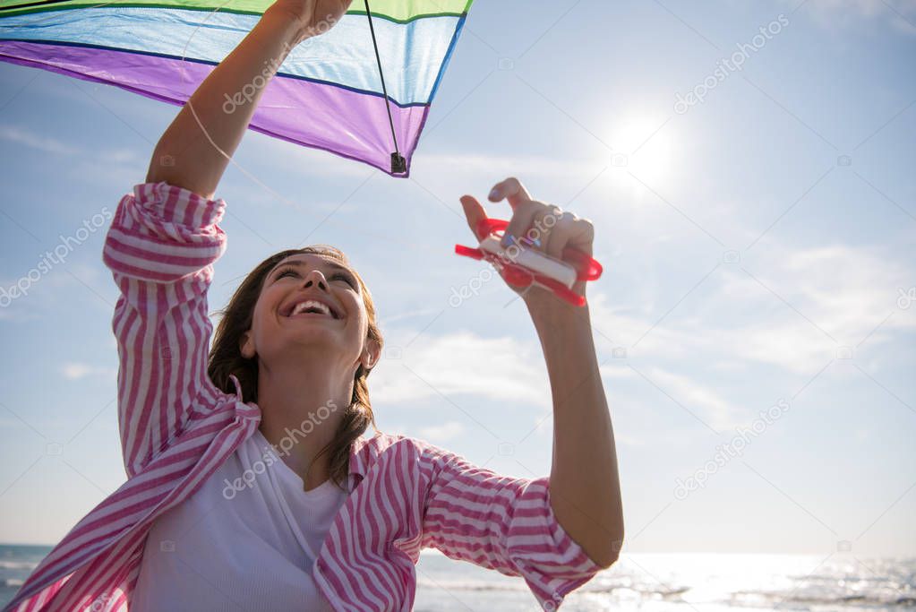 Beautiful Young Woman having fun with a kite at Beach on autumn day