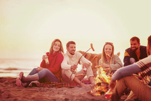 Grupo Jóvenes Amigos Sentados Junto Fuego Playa Otoño Asando Salchichas — Foto de Stock