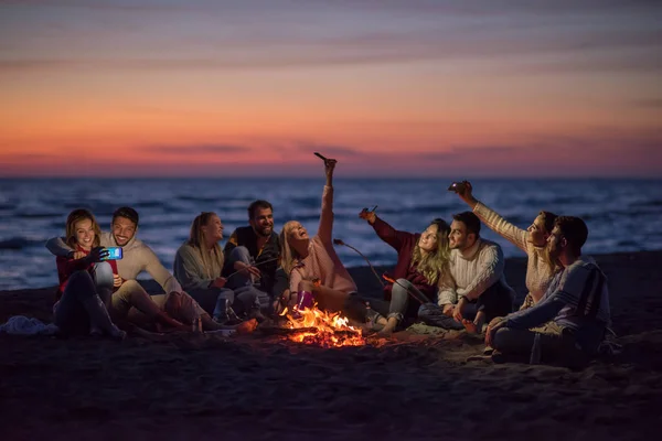 Grupo Amigos Usando Telefones Celulares Redor Fogueira Durante Festa Praia — Fotografia de Stock