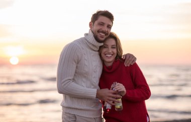 Genç çift gün ışığında sarılıyor ve bira içiyor.