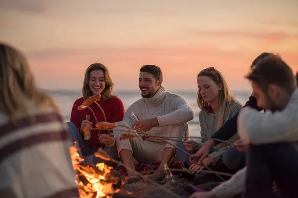 Grupo Jóvenes Amigos Sentados Junto Fuego Playa Otoño Asando Salchichas — Foto de Stock