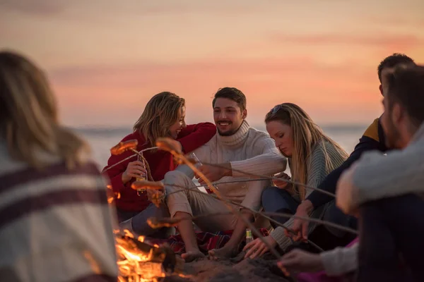 Group Young Friends Sitting Fire Autumn Beach Grilling Sausages Drinking — Stock Photo, Image