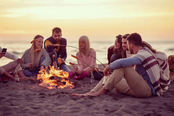 Skupina Mladých Přátel Sedících Krbu Podzimní Pláži Grilujících Klobás Popíjejících — Stock fotografie