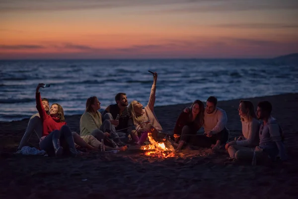 Grupo Amigos Usando Telefones Celulares Redor Fogueira Durante Festa Praia — Fotografia de Stock