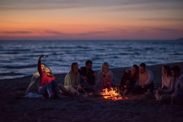 Gruppo Amici Che Usano Cellulari Intorno Falò Durante Festa Spiaggia — Foto Stock