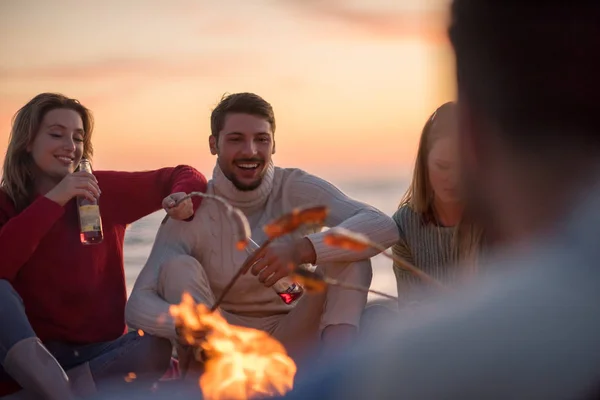 Group Young Friends Sitting Fire Autumn Beach Grilling Sausages Drinking — Stock Photo, Image