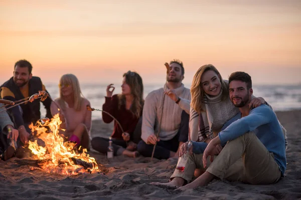 Grupo Jóvenes Amigos Sentados Junto Fuego Playa Otoño Asando Salchichas —  Fotos de Stock