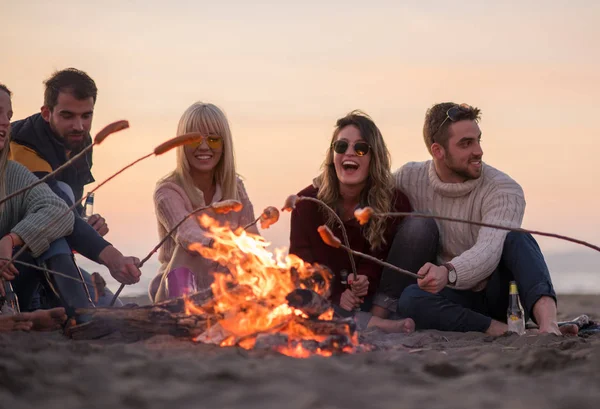 Grupo Jóvenes Amigos Sentados Junto Fuego Playa Otoño Asando Salchichas — Foto de Stock