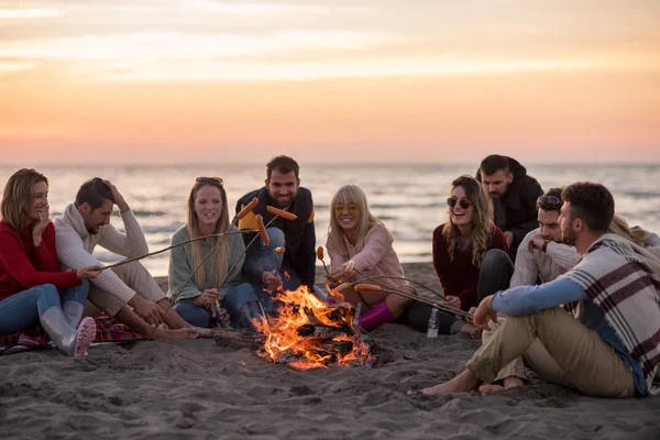 Grupo Jovens Amigos Sentados Lado Fogo Praia Outono Grelhando Salsichas — Fotografia de Stock