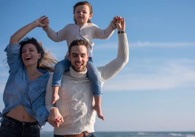 Çocukların dinlendiği ve sonbahar günü kumsalda eğlendiği bir aile.