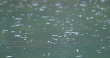 Ağır çekimde göl yüzeyinde yağmur damlaları