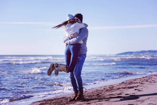 秋日阳光明媚的日子里 年轻夫妇在海滩上散步和拥抱 玩得很开心 — 图库照片