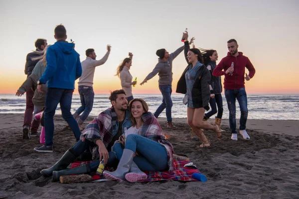 Fiatal Pár Élvezi Barátaival Körül Tábortűz Strandon Naplementekor Sört Iszik — Stock Fotó